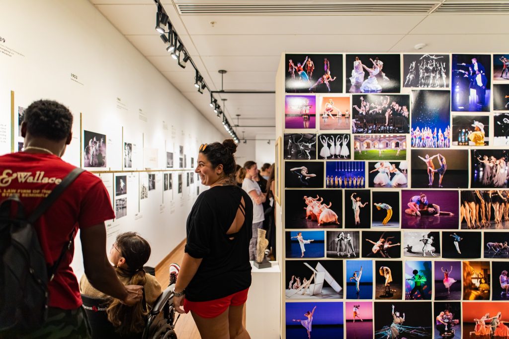 people gather in a gallery admiring photos of dancers