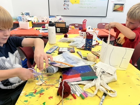 there are two boys that are sitting at a table with art supplies
