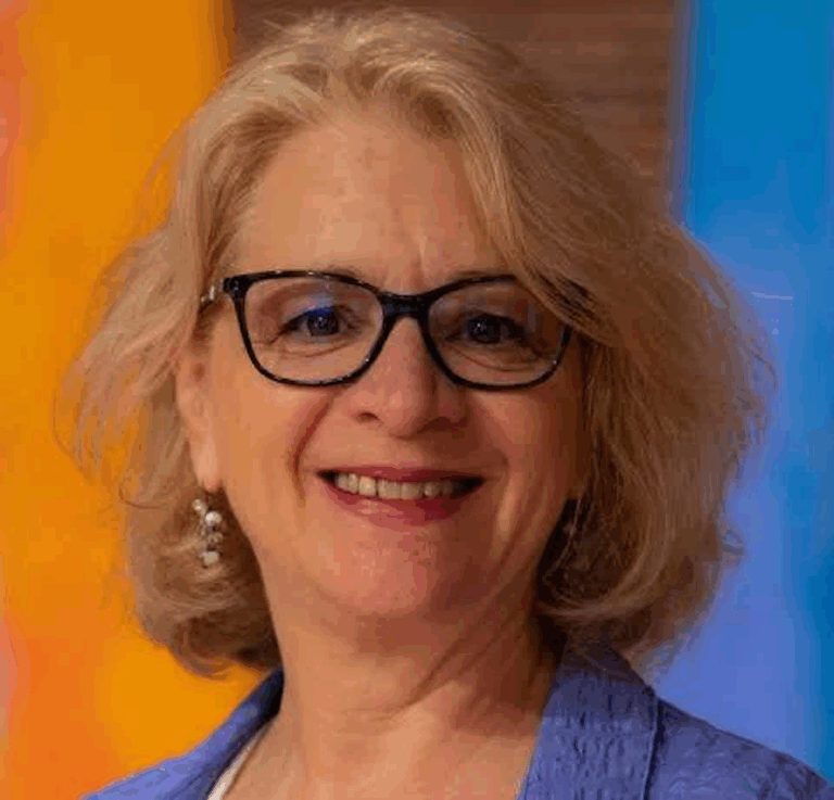 there is a woman with glasses and a blue shirt smiling