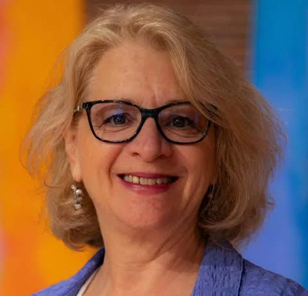 A smiling woman wearing dark rimmed glasses, 