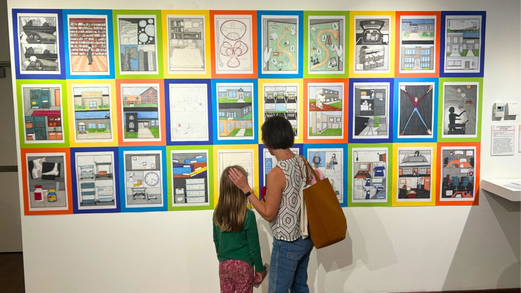 Two people look at artwork on a wall