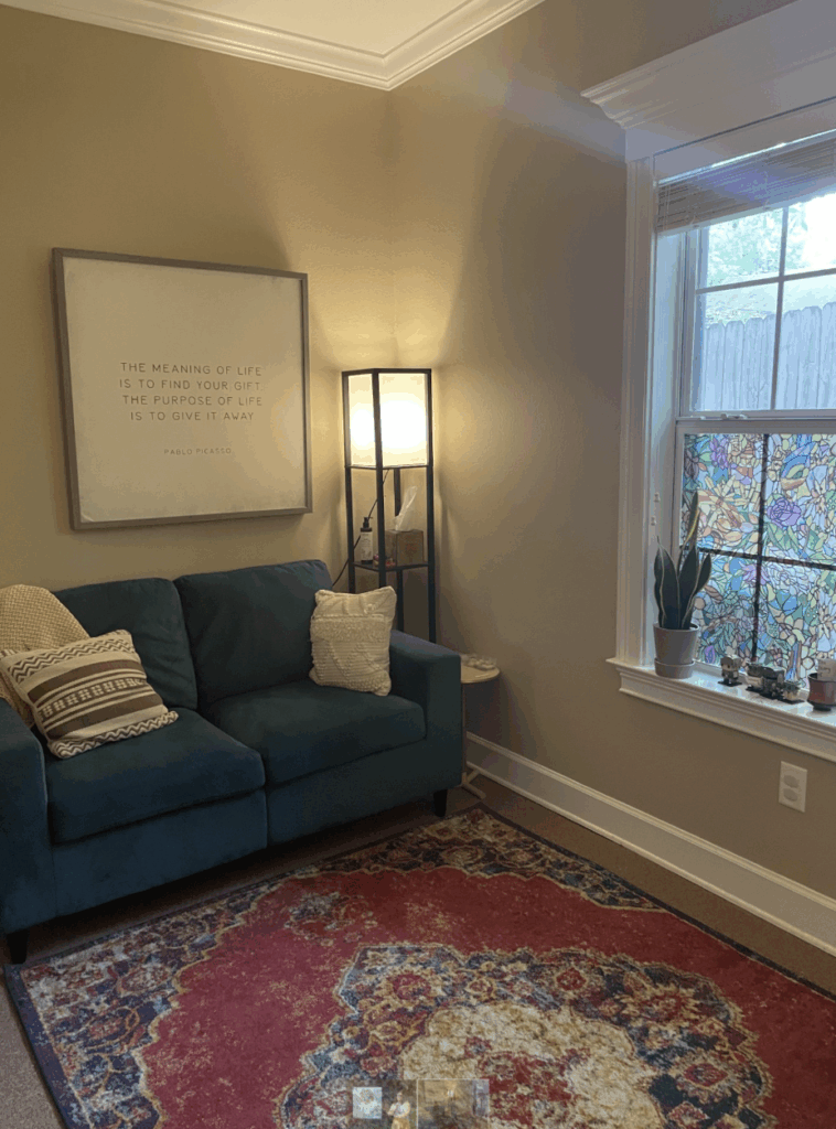 A cozy room with a colorful rug and a blue couch. 
