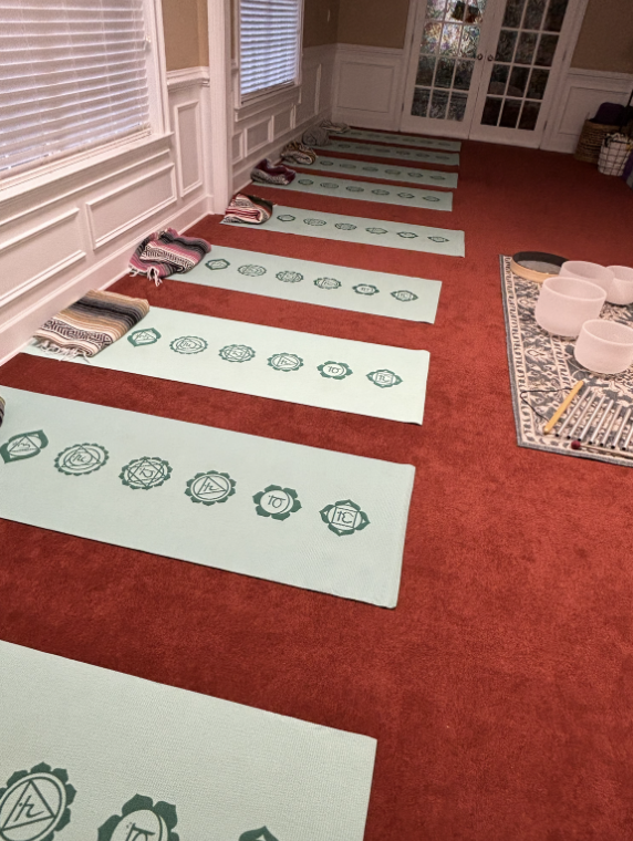 Yoga mats are lined up along a well on red carpet. 