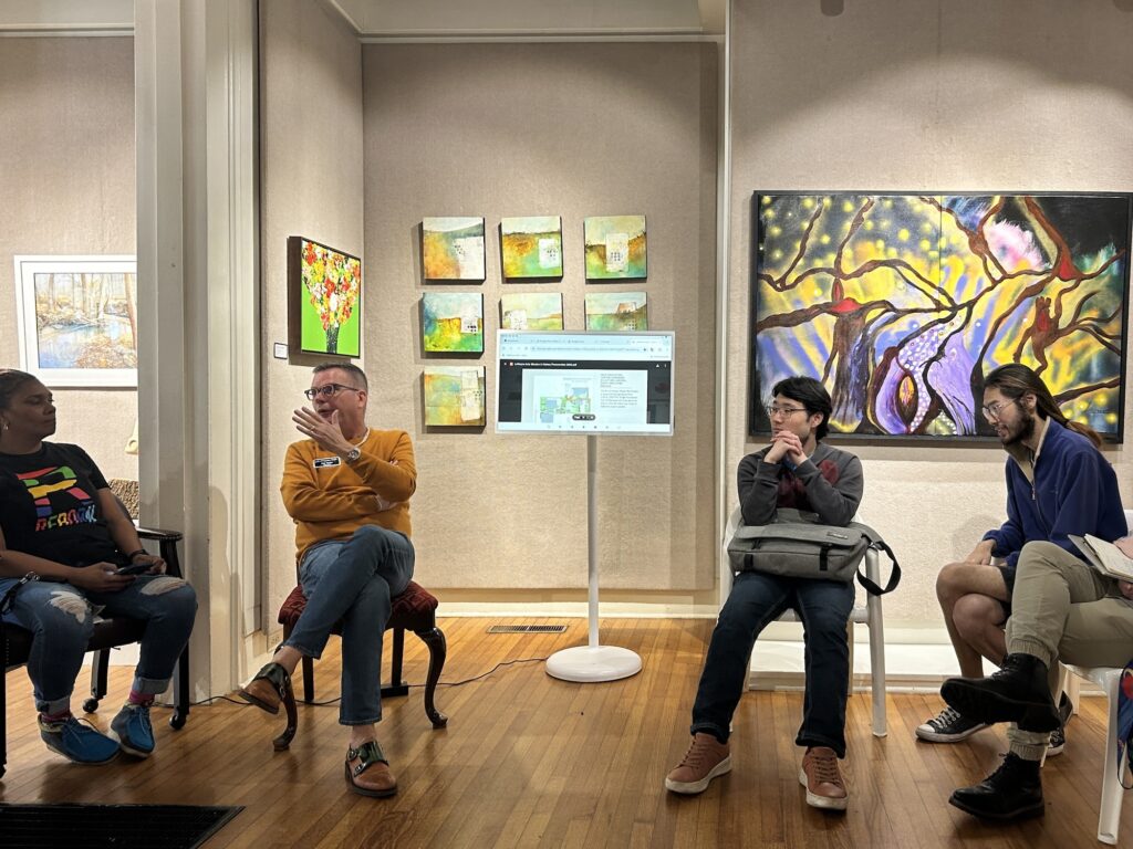 A group of people seated in an art gallery having a discussion
