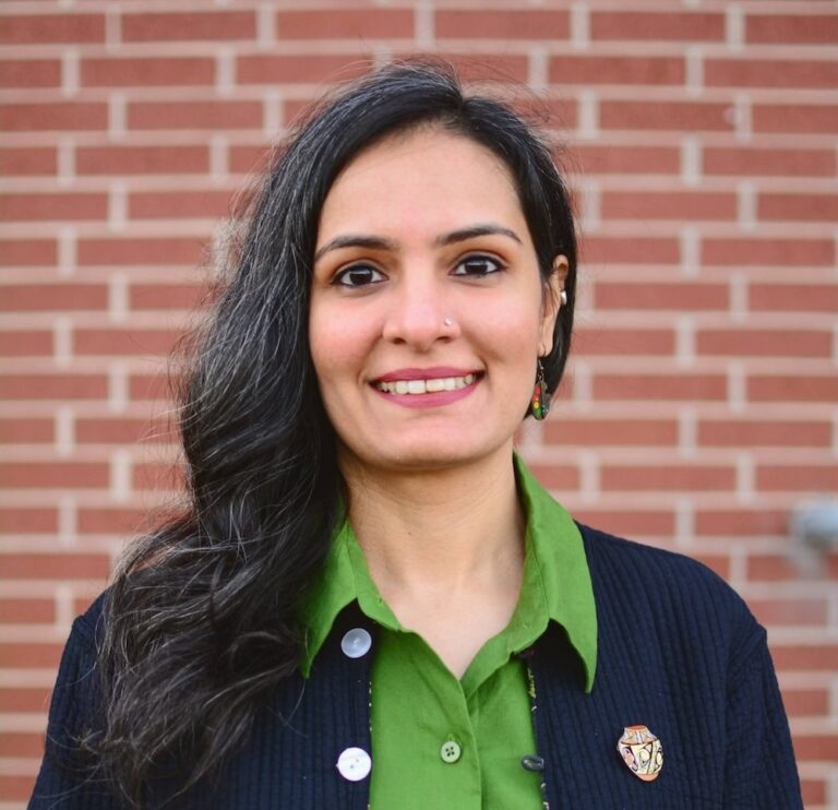 A woman poses in front of a brick wall