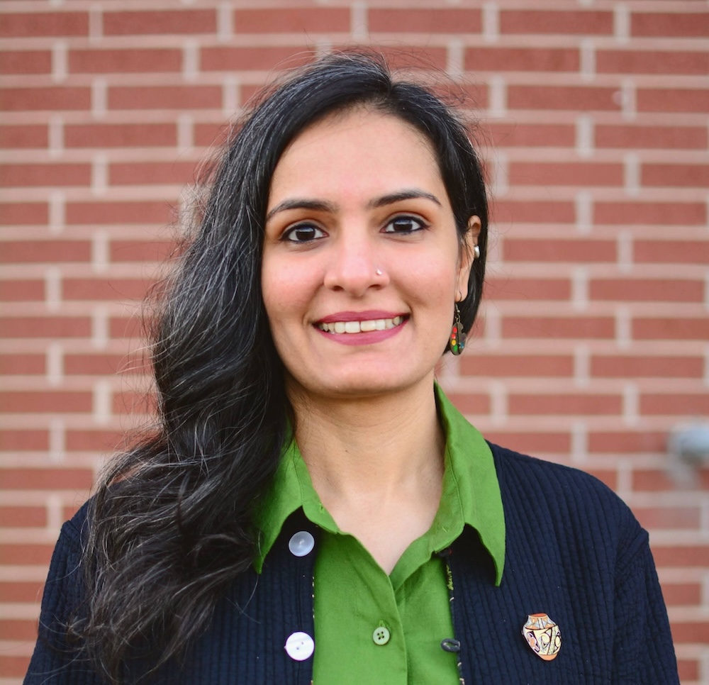 A woman poses in front of a brick wall